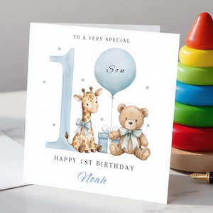May include: A square white greeting card featuring a large blue number one, a watercolor giraffe with a blue bow, a light blue balloon labeled Son, a brown teddy bear with a blue bow, and a gift box. Text reads To a very special, Happy 1st Birthday, and Noah.