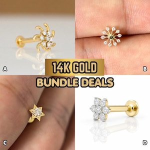 May include: A collection of four 14K gold body jewelry pieces labeled A, B, C, and D. Item A is a gold stud with a swirling starburst design. Item B is a gold sunburst stud. Item C is a gold star-shaped stud. Item D is a gold flower-shaped stud.