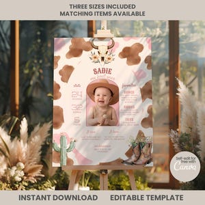 May include: A milestone birthday poster template featuring a cow print background, a central photo of a baby wearing a hat, a bull skull illustration, a cactus, and cowboy boots. Text includes "SADIE", "my first year", "stats", "favorites", "I can", "I love", and "NICKNAMES".