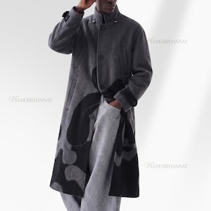 May include: A long, charcoal gray coat featuring a high collar, front button closure, and large black abstract patterns across the lower section. The coat has long sleeves with buttoned cuffs and side pockets. The text VELOURBYJANNAT is visible.