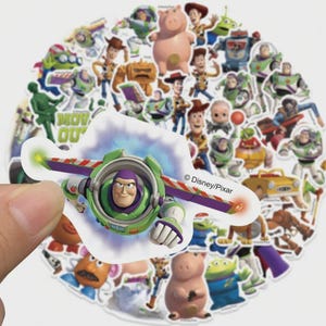 May include: A collection of colorful Toy Story character stickers, including Buzz Lightyear, Woody, and others. The stickers feature various poses and designs from the animated film series. The Disney/Pixar logo is visible on one of the stickers.