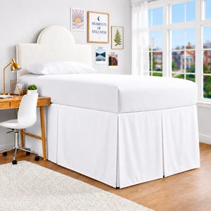 May include: A white bed valance featuring a tailored, pleated design that conceals the base of a bed. The fabric is solid white and opaque, extending from the mattress down to the floor, providing a clean, uniform look for the bed frame.