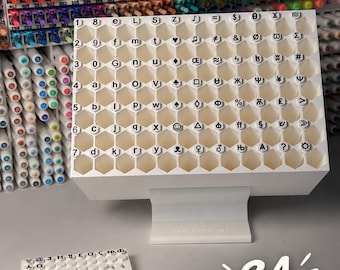 Könnte beinhalten: Ein weißer 3D-gedruckter Organizer mit 84 sechseckigen Fächern für Marker, mit aufgedruckten alphanumerischen Zeichen und Symbolen auf dem vorderen Gitter. Ein kleineres passendes weißes Gittertablett steht links, Text 84 SLOTS.