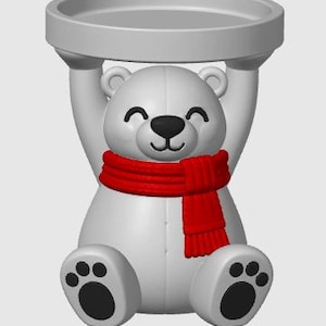 May include: A white polar bear figurine with a black nose and paw pads, wearing a bright red scarf. The bear is in a seated position with its arms raised above its head, supporting a circular, flat-topped tray in a matching white finish.