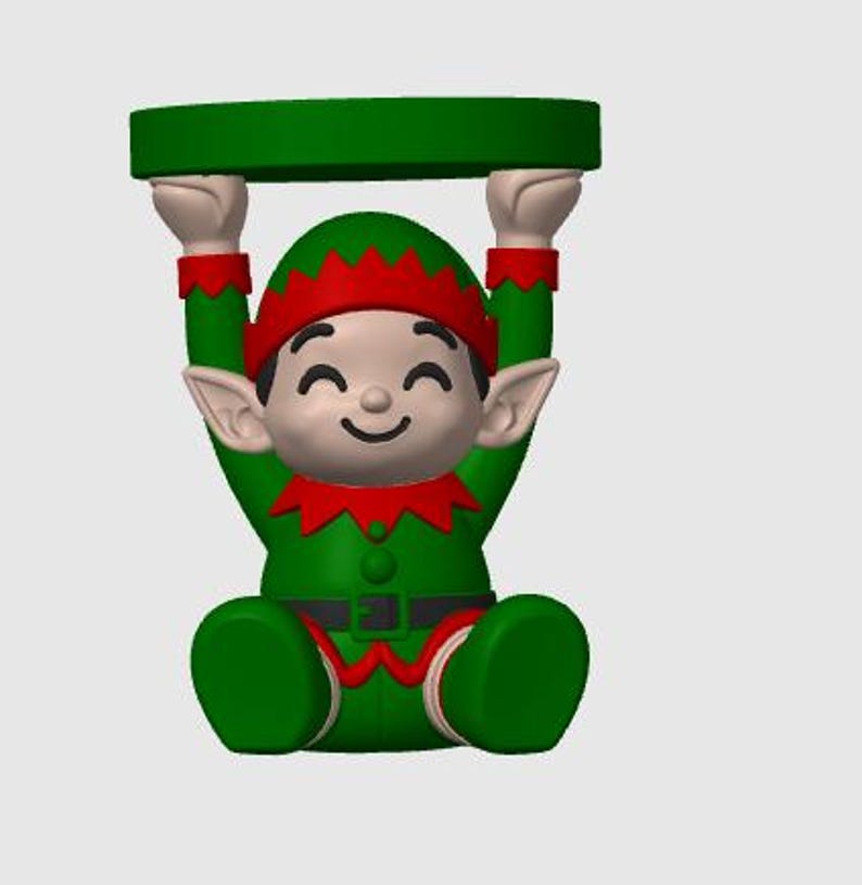 May include: A figurine of a smiling elf wearing a green and red outfit with a pointed hat and collar. The elf is in a seated position with arms raised above its head, supporting a flat, circular green platform balanced on its hands.
