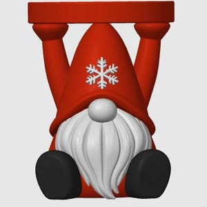 May include: A red gnome figurine standing on its head with its arms extended upward to support a flat red circular base. The gnome features a tall red pointed hat adorned with a white snowflake emblem, a white nose, and a long white beard.