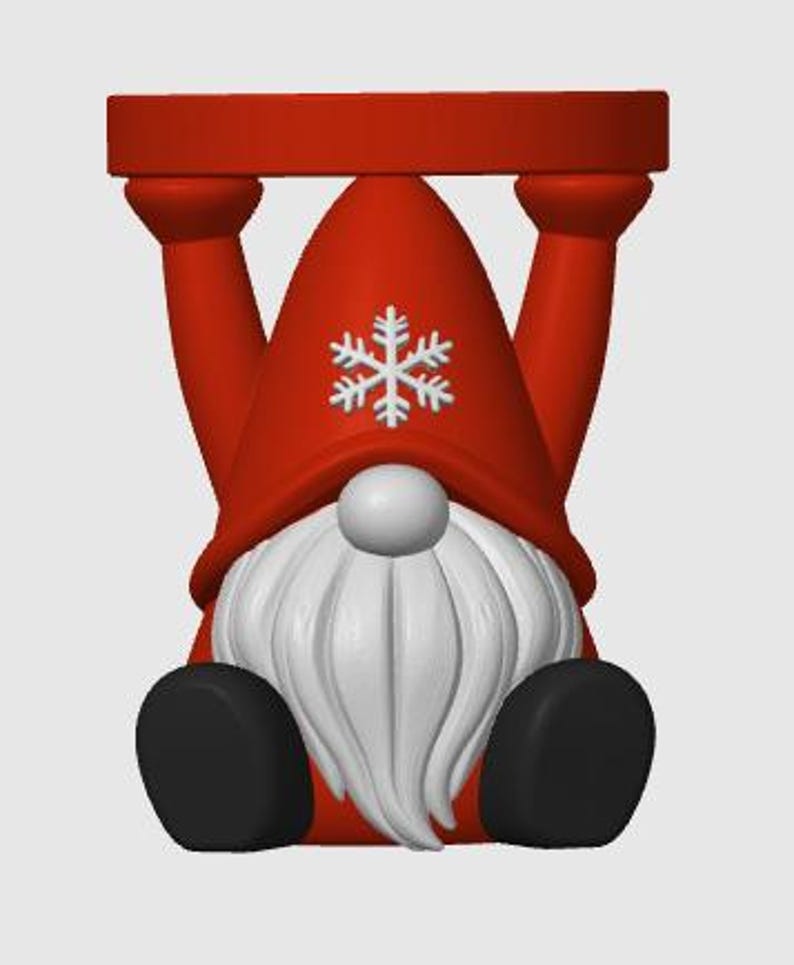 May include: A red gnome figurine standing on its head with its arms extended upward to support a flat red circular base. The gnome features a tall red pointed hat adorned with a white snowflake emblem, a white nose, and a long white beard.