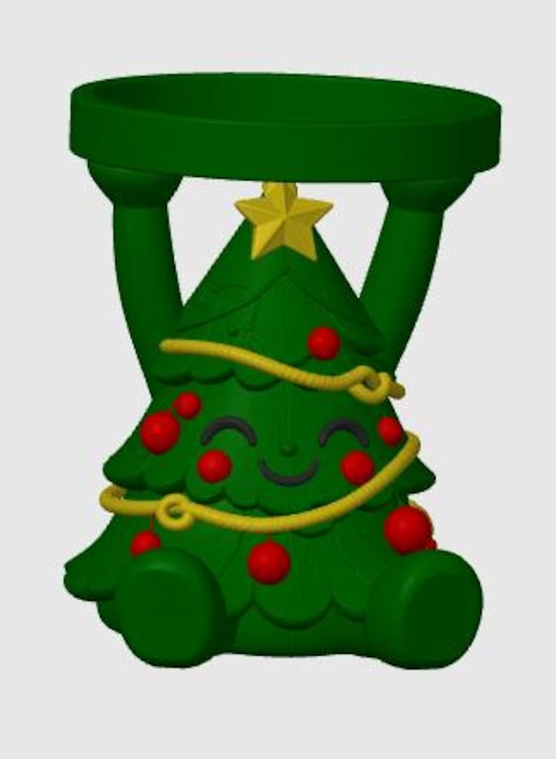May include: A green Christmas tree-shaped candle holder featuring a smiling face, red ornaments, and a yellow garland. The tree is topped with a yellow star and has two arms extending upward to support a circular green platform at the top.
