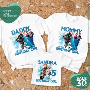 three white t-shirts with the same design, each with a different character from the Disney movie Frozen. The design includes the characters Elsa, Anna, Olaf, and other popular characters from the movie. The t-shirts are arranged on a bed of straw, and there is a sale sign indicating a 30% discount on the t-shirts.