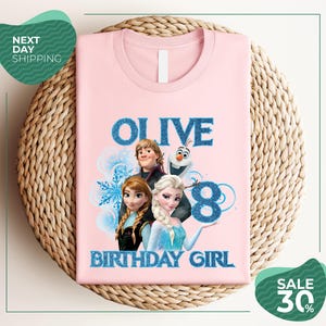 A pink t-shirt with a graphic design featuring characters from the Disney movie Frozen, specifically Olive, and the text "OLIVE 8 BIRTHDAY GIRL".