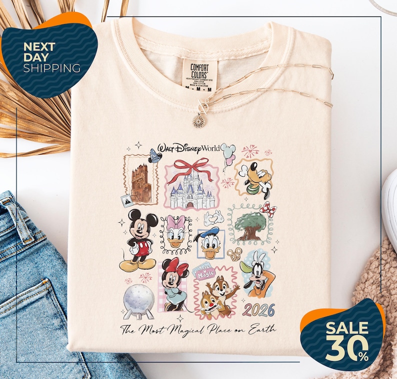 a white t-shirt with a Disney World-themed graphic, including various Disney characters and landmarks, such as Mickey Mouse, Minnie Mouse, Donald Duck, and the Eiffel Tower. The t-shirt is displayed on a white background, and there are jeans visible in the background. The image also includes text that reads "Next Day Shipping" and "SALE 30%".