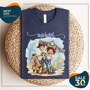 A t-shirt featuring characters from the Toy Story franchise, including Woody, Buzz Lightyear, and a girl, along with a horse and a dog.