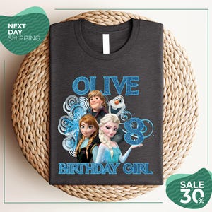 A gray t-shirt with a graphic design featuring characters from the Disney movie Frozen, specifically Olive, the birthday girl.