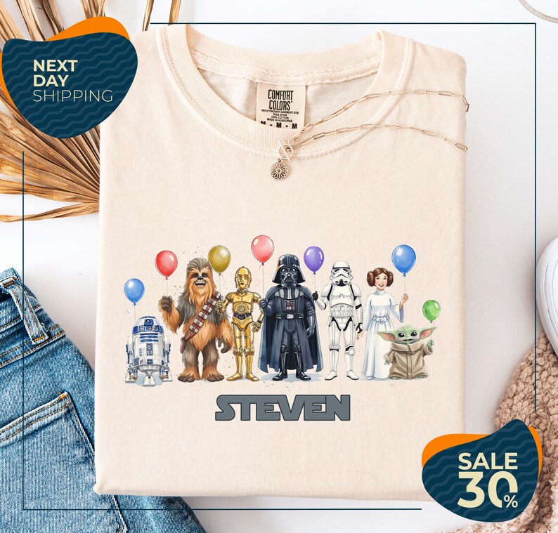 a t-shirt with a graphic design of various Star Wars characters, including Chewbacca, Darth Vader, Stormtrooper, and Yoda, along with balloons. The t-shirt is displayed on a white background, and there are two sale signs indicating a 30% discount on the item.