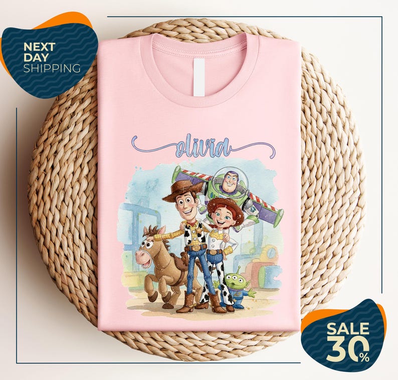 A pink t-shirt featuring characters from the Toy Story movie, including Woody, Buzz Lightyear, and a girl, along with a horse and a dog.