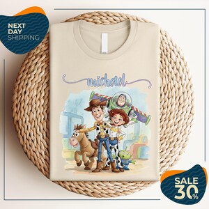 a t-shirt with a cartoon illustration of characters from the Toy Story franchise, including Woody, Buzz Lightyear, and a girl. The t-shirt is displayed on a woven basket, and there are two sale signs indicating a 30% discount on the item.