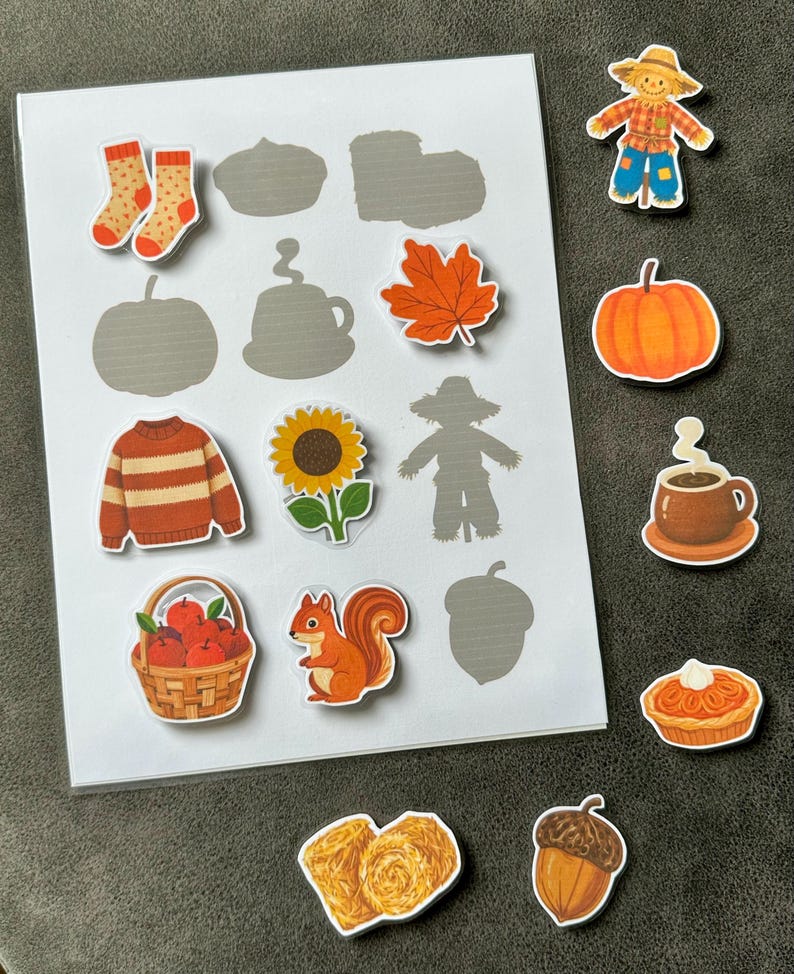 May include: A matching activity sheet featuring a white card with gray silhouettes of autumn items and several colorful die-cut stickers including a scarecrow, pumpkin, coffee mug, pie, acorn, socks, sweater, sunflower, squirrel, apple basket, and hay bales.