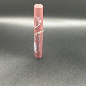 May include: A mauve-colored lipstick tube with the text "JVLL08 TIP TOE" printed on the label. The tube is cylindrical with a rounded top. The label is partially peeled back, revealing additional text and a barcode.