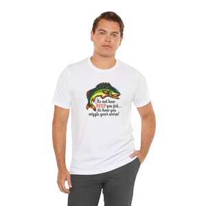 Può includere: T-shirt bianca con un'illustrazione colorata di un pesce e la scritta "Its not how DEEP you fish... its how you wiggle your worm!". Il pesce è verde, giallo, rosso e blu. Un capo casual per tutti i giorni.