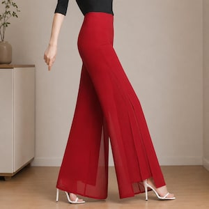 May include: High-waisted red wide-leg trousers featuring a solid opaque inner layer and a sheer, flowing outer layer. The pants have a clean, minimalist silhouette with a side slit design that reveals the layered fabric construction.