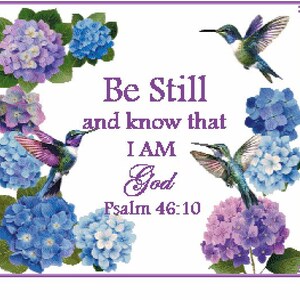 May include: A decorative print featuring the text Be Still and know that I AM God Psalm 46:10 in purple lettering, surrounded by vibrant blue and purple hydrangea flower clusters and three colorful hummingbirds in flight on a white background.