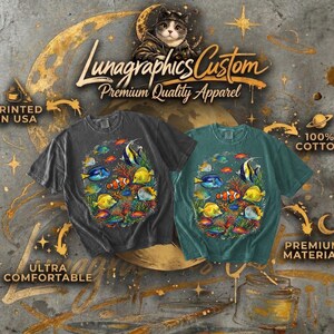 May include: Two t-shirts, one charcoal and one teal, feature a colorful underwater scene with various fish. The shirts are labeled "Lunagraphics Custom Premium Quality Apparel" and are made of 100% cotton. The shirts are printed in the USA and are ultra comfortable.