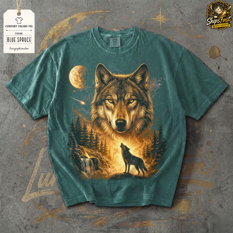 May include: Blue spruce comfort colors tee featuring a detailed wolf illustration. The design includes a large wolf head, a howling wolf, a moon, and a forest scene. The tag reads "Comfort Colors Tee" and "Blue Spruce".