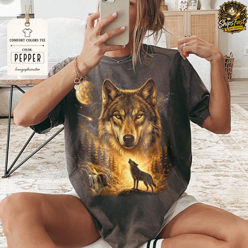 May include: Pepper-colored Comfort Colors tee featuring a detailed wolf illustration. The design includes a large wolf face, a howling wolf, a waterfall, and a starry night sky. The tag reads "COMFORT COLORS TEE" and "PEPPER".