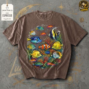 May include: Espresso-colored Comfort Colors tee featuring a vibrant illustration of various colorful fish swimming around coral. The design includes clownfish, angelfish, and other tropical species. The shirt has a relaxed fit and a vintage look.