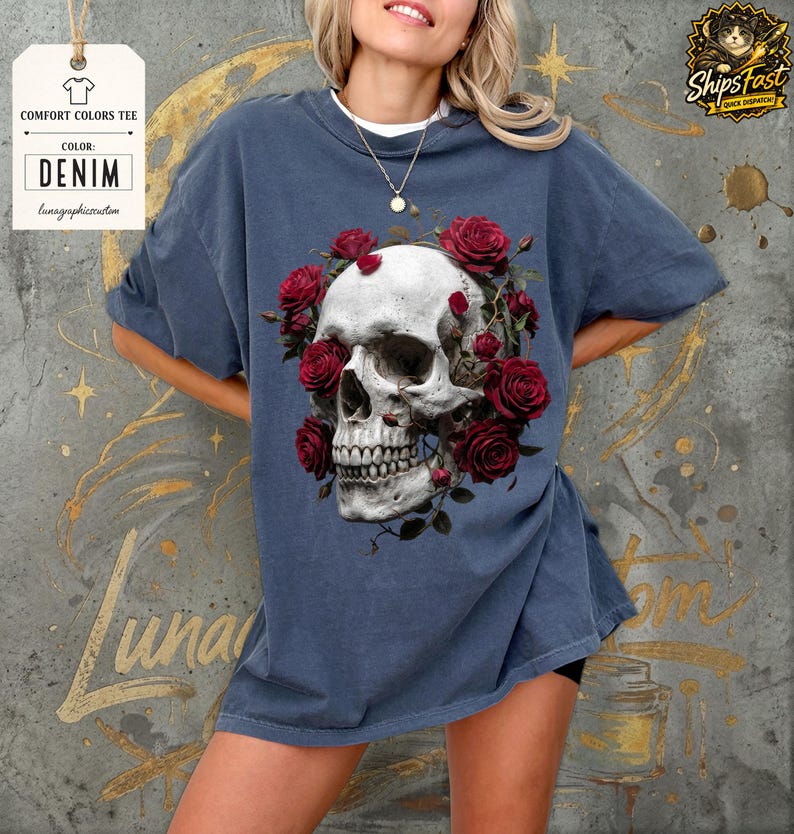 May include: Denim blue Comfort Colors tee featuring a detailed skull design encircled by red roses. The graphic tee includes the text "Comfort Colors Tee" and "Color: Denim". The shirt is from lunagraphicreation.