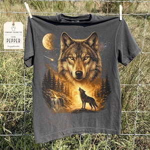 May include: Dark gray Comfort Colors tee featuring a detailed wolf graphic. The design includes a large wolf face, a howling wolf, a moon, and a forest scene. The tag reads "COMFORT COLORS TEE" and "COLOR PEPPER".