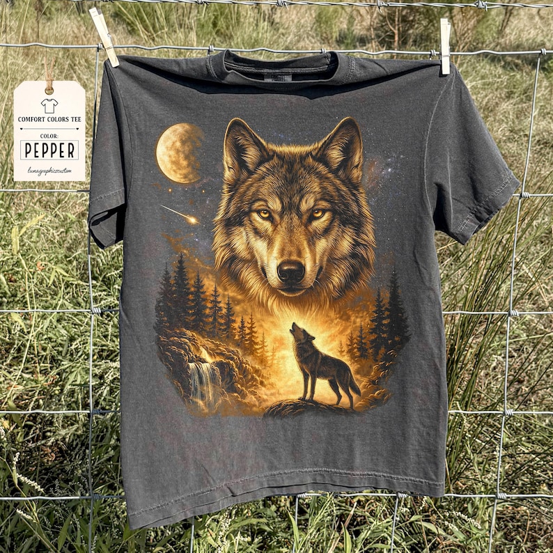 May include: Dark gray Comfort Colors tee featuring a detailed wolf graphic. The design includes a large wolf face, a howling wolf, a moon, and a forest scene. The tag reads "COMFORT COLORS TEE" and "COLOR PEPPER".