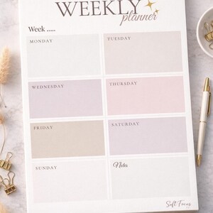 May include: A weekly planner with a gold spiral binding, featuring the text "WEEKLY planner". It has sections for each day, in a soft colour palette of beige, pink, and lavender. Includes a pen and stationery.