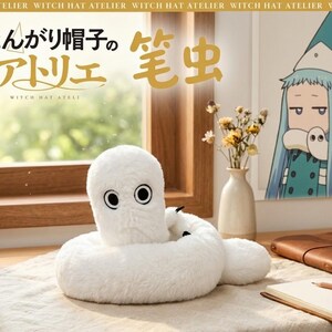 May include: A white plush toy shaped like a worm with large, round eyes and a ring-shaped body. The toy is on a light-colored surface, with a window and a drawing of a character in the background. The text "Witch Hat Atelier" is visible.
