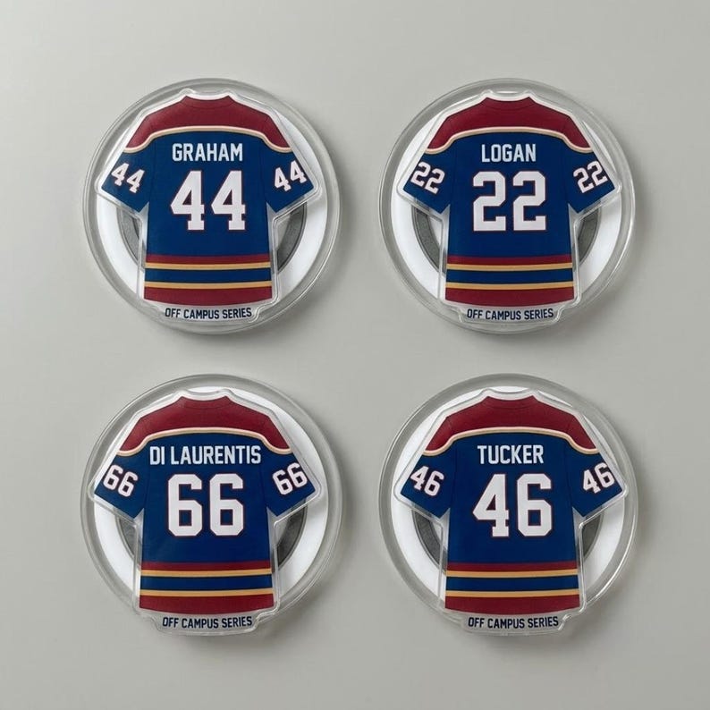 May include: Four circular magnets with miniature hockey jerseys. Each navy blue jersey has white numbers and red and gold trim. The names Graham, Logan, Di Laurentis, and Tucker are printed above the numbers. The text "OFF CAMPUS SERIES" is printed at the bottom of each magnet.