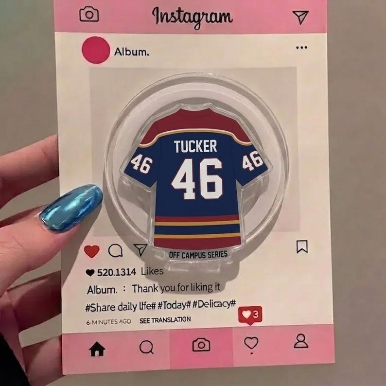 May include: A clear acrylic phone grip in the shape of a blue and red jersey, featuring the name "TUCKER" and the number "46". The grip is set against a pink Instagram-themed background with text including "Album" and "520.1314 Likes".