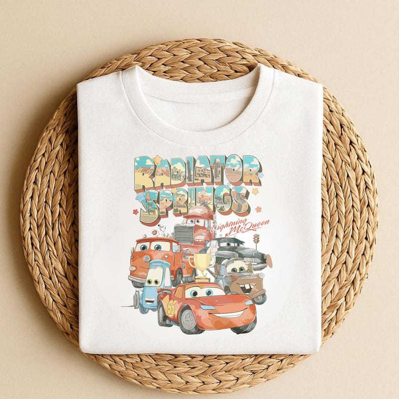 May include: A white ceramic mug with a black handle and the text "But First, Coffee" in a bold, black font. The mug is set against a blurred background, suggesting a cozy setting.