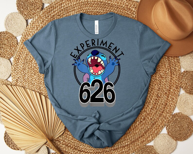 May include: A blue t-shirt with a cartoon character and the text "EXPERIMENT 626". The character is blue with an open mouth and raised arms. The number 626 is in large black numbers.