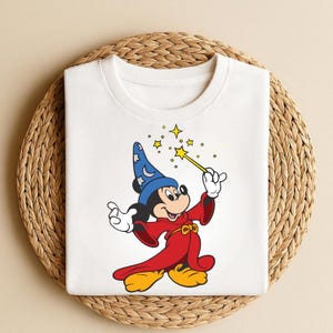 May include: A white ceramic mug with a black handle and the text "But First, Coffee" in a bold, black font. The mug is set against a blurred background, suggesting a cozy setting.