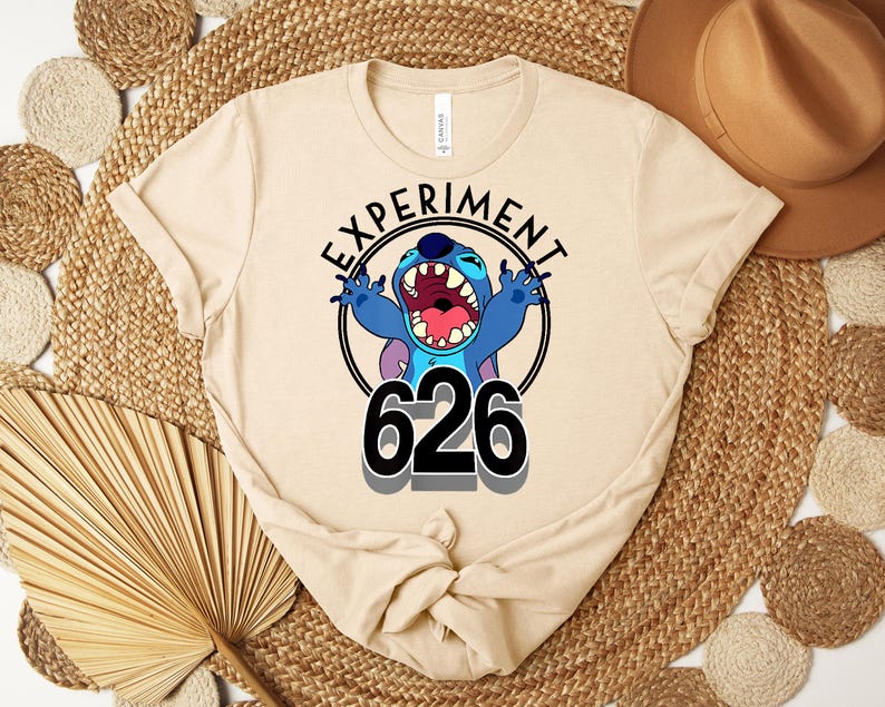 May include: A beige t-shirt with a graphic of the character Stitch from Lilo & Stitch. The design includes the text "EXPERIMENT" above the character and the number "626" below. Stitch is blue with an open mouth and raised arms.