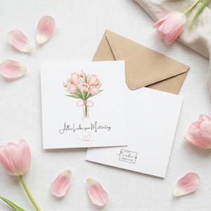 Pode incluir: Um cartão de felicitações branco com uma ilustração em aquarela de tulipas cor-de-rosa amarradas com uma fita. O cartão tem o texto "Alles Liebe zum Muttertag", com um envelope de papel kraft e pétalas espalhadas.
