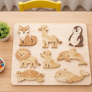 May include: Wooden animal puzzle featuring a fox, giraffe, penguin, lion, dog, dolphin, turtle, and whale. The puzzle pieces are light brown and tan, arranged on a light wood board. A small plant and a bowl of colorful balls are also present.
