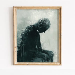 Könnte beinhalten: Abstrakter Kunstdruck mit einer sitzenden Figur in Dunkelblaugrün- und Grautönen. Das Kunstwerk ist in einem goldfarbenen Holzrahmen gerahmt. Die Figur ist in einer nachdenklichen Pose dargestellt, mit gesenktem Kopf. Der Hintergrund ist strukturiert und gedämpft grau.
