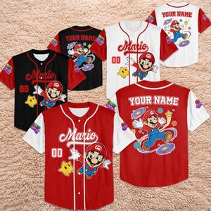 Może przedstawiać: Koszulki baseballowe w kolorze czerwonym, czarnym i białym, z postacią Mario. Każda koszulka ma inny wz&oacute;r, z napisem "Mario" i numerem "00" z przodu. Niekt&oacute;re koszulki mają nadruk "YOUR NAME" z tyłu.