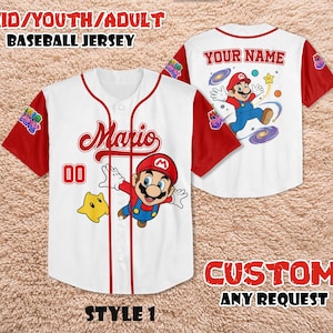 Może przedstawiać: Biała koszulka baseballowa z czerwonymi rękawami i akcentami, z grafiką Mario z przodu i z tyłu. Prz&oacute;d przedstawia napis "Mario" w czerwonym kolorze, numer "00" i postać z kresk&oacute;wki Mario. Tył ma miejsce na niestandardowe imię.