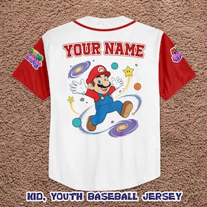 Może przedstawiać: Biała koszulka baseballowa z czerwonymi rękawami i kołnierzem. Zawiera kresk&oacute;wkowy wizerunek Mario z napisem "YOUR NAME" nad obrazkiem. Koszulka ma r&oacute;wnież napis "KID, YOUTH BASEBALL JERSEY" na dole.