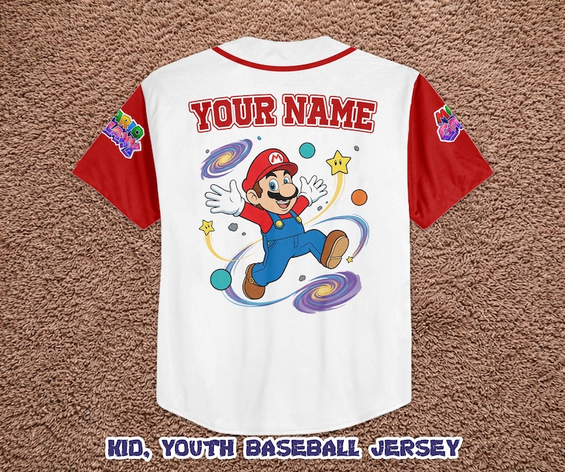 Może przedstawiać: Biała koszulka baseballowa z czerwonymi rękawami i kołnierzem. Zawiera kresk&oacute;wkowy wizerunek Mario z napisem "YOUR NAME" nad obrazkiem. Koszulka ma r&oacute;wnież napis "KID, YOUTH BASEBALL JERSEY" na dole.