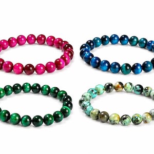 Peut inclure: Quatre bracelets de perles de couleurs rose, bleu, vert et un mélange de vert, marron et jaune. Chaque bracelet est composé de perles rondes et polies. Les bracelets sont présentés sur fond blanc.