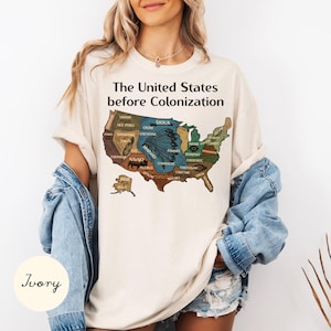May include: Ivory-colored t-shirt featuring a map of the United States before colonization, with tribal names. The text "The United States before Colonization" is printed above the map. The shirt is a casual, comfortable style.