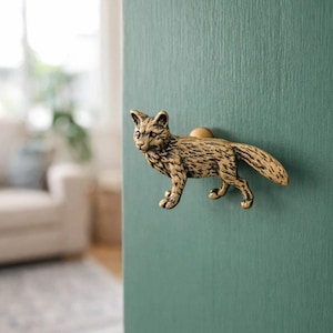 May include: A brass fox door knob fixed to a teal door. The fox is in a walking position, with detailed fur. The knob is a decorative element. The door is painted in a teal colour, adding a touch of whimsy.